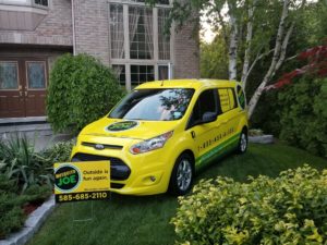 Yellow Mosquito Joe service van and yard sign placed beside a Rochester home 